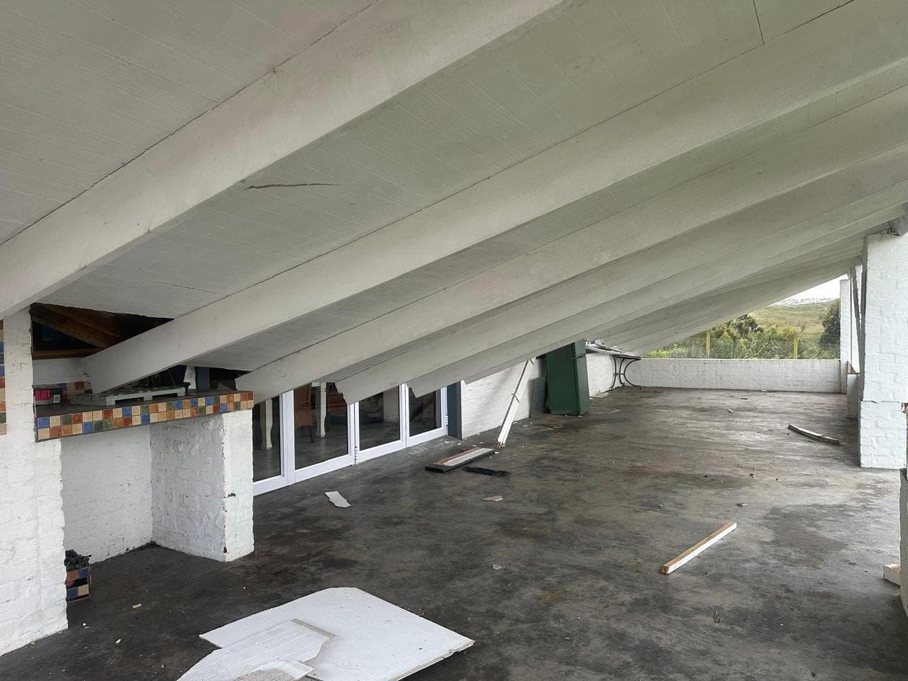 Veranda ceiling boards torn loose by the storm, debris across the floor