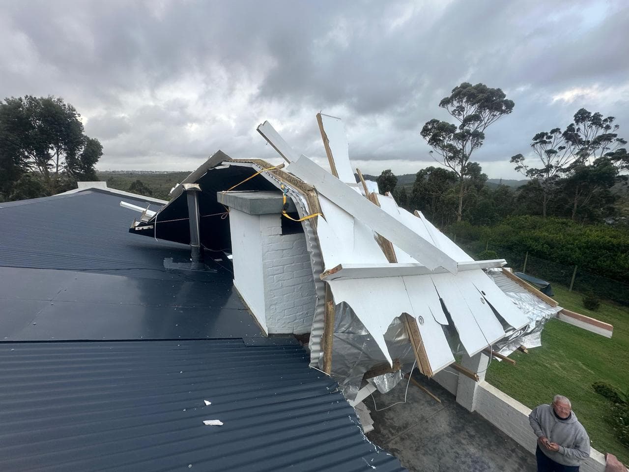 Roof edge and ceiling sheets ripped up and hanging over the gutter line