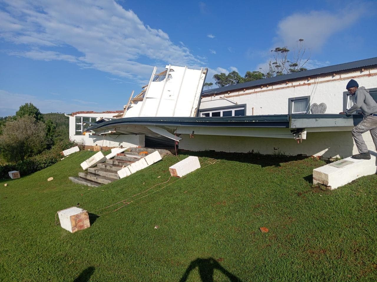 The full veranda soffit torn away, insulation blocks scattered across the lawn