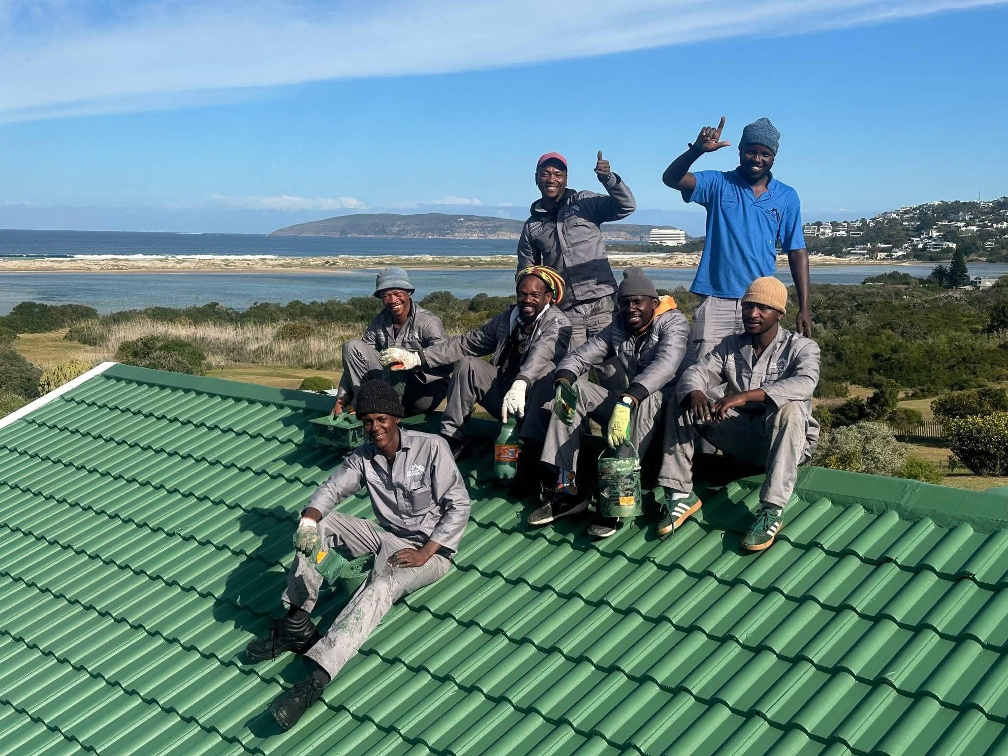 The Roof Doctor team on a freshly painted roof above the Plettenberg Bay lagoon